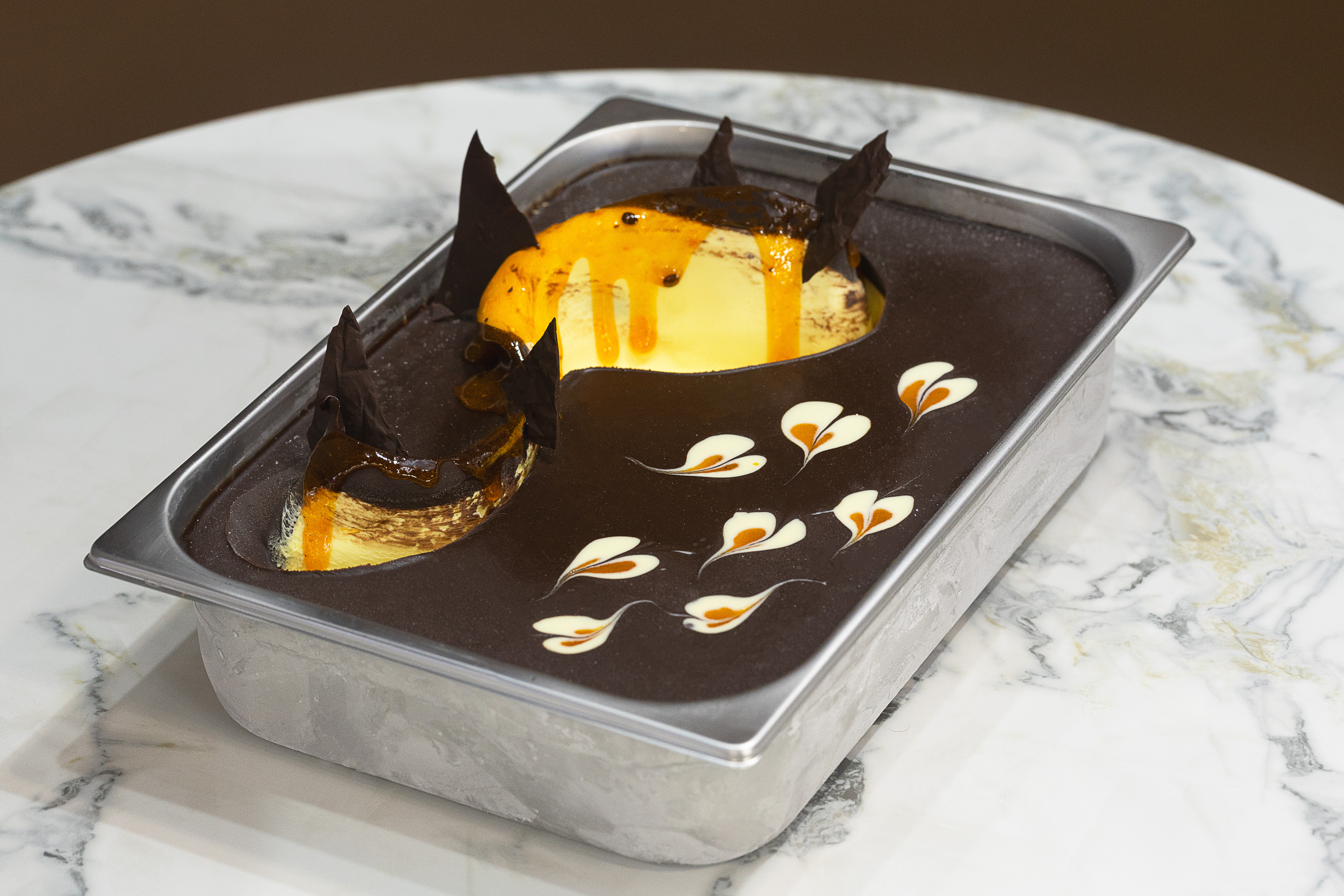 foto de uma cuba de gelato de maracujá coberto por variegato maracujá e stracciatella de chocolate meio amargo