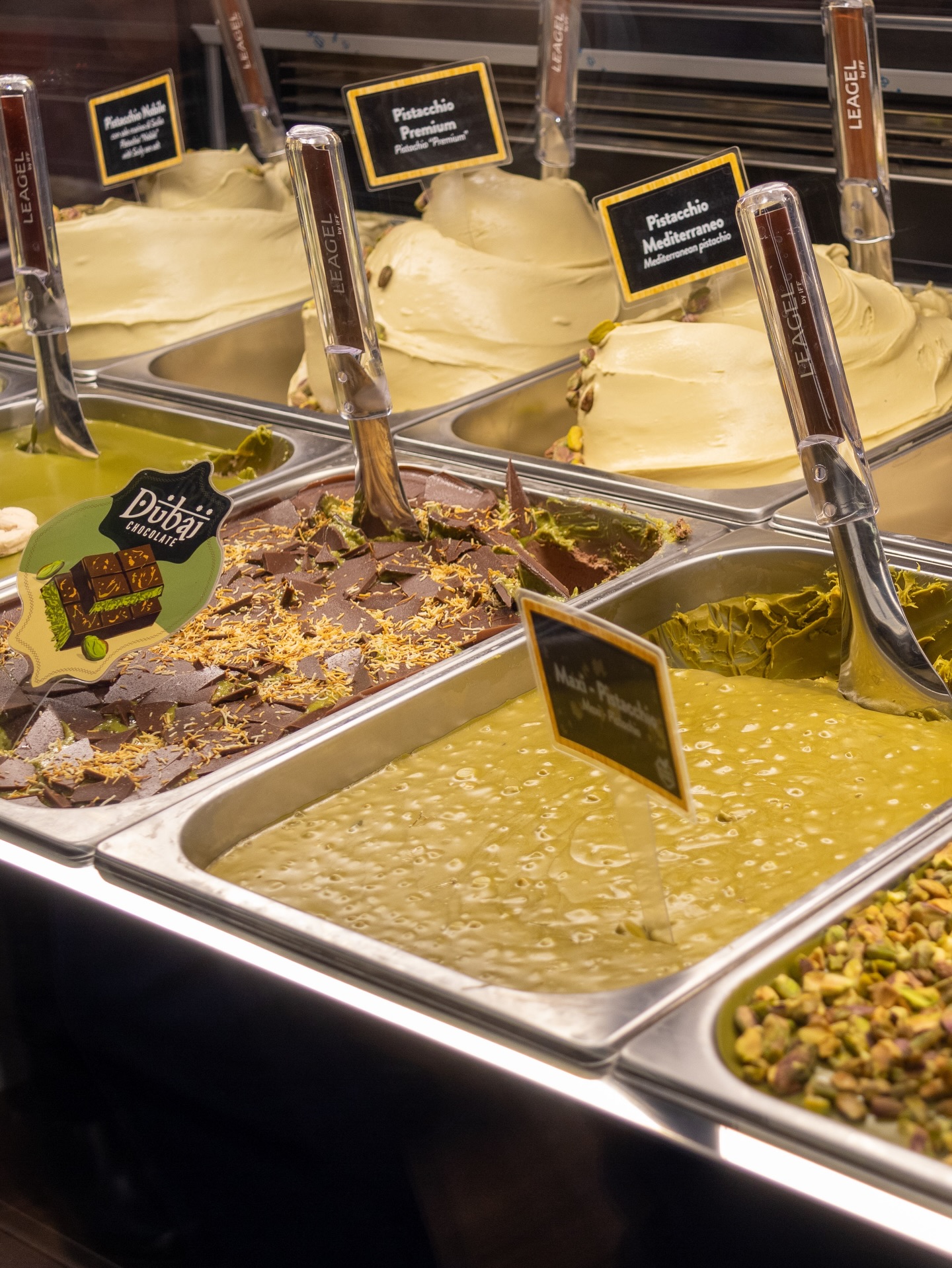  Foto de uma vitrine de gelatos de pistache com diferentes aplicações, texturas e combinações.
